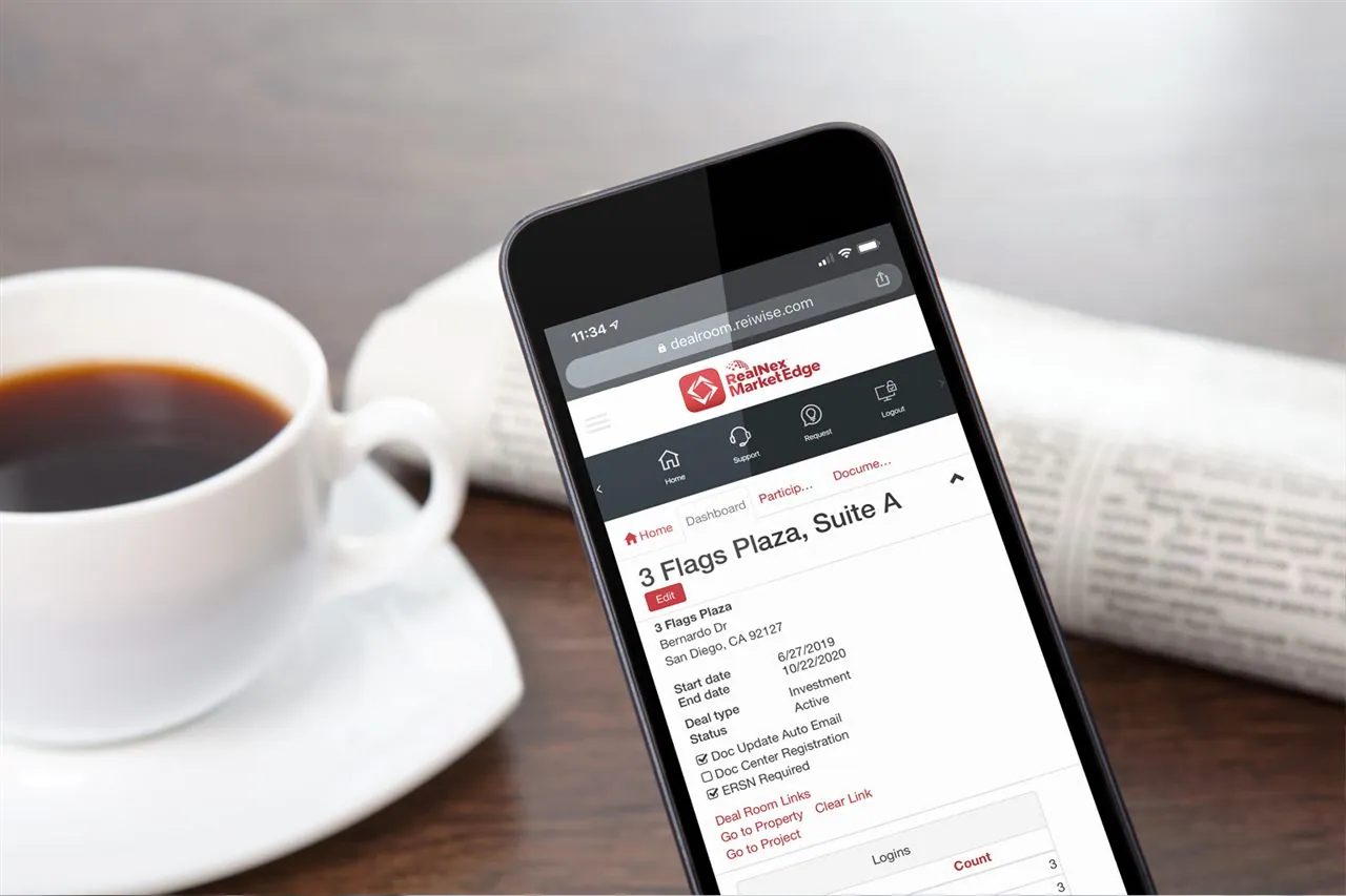 Smartphone displaying RealNex app next to coffee on a desk