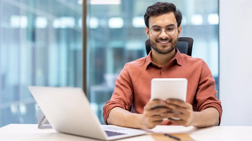Professional smiling while looking at a tablet at his desk